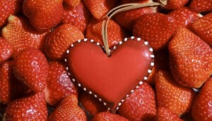 Corazón rojo entre fresas. Aprende a usar los emojis de corazón ¿Sabes su significado?