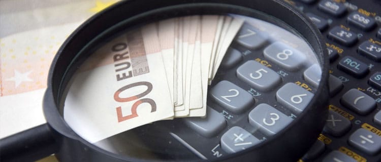 Calculadora, dinero y lupa en 7 Desafíos y trucos para ahorrar si tu presupuesto es bajo